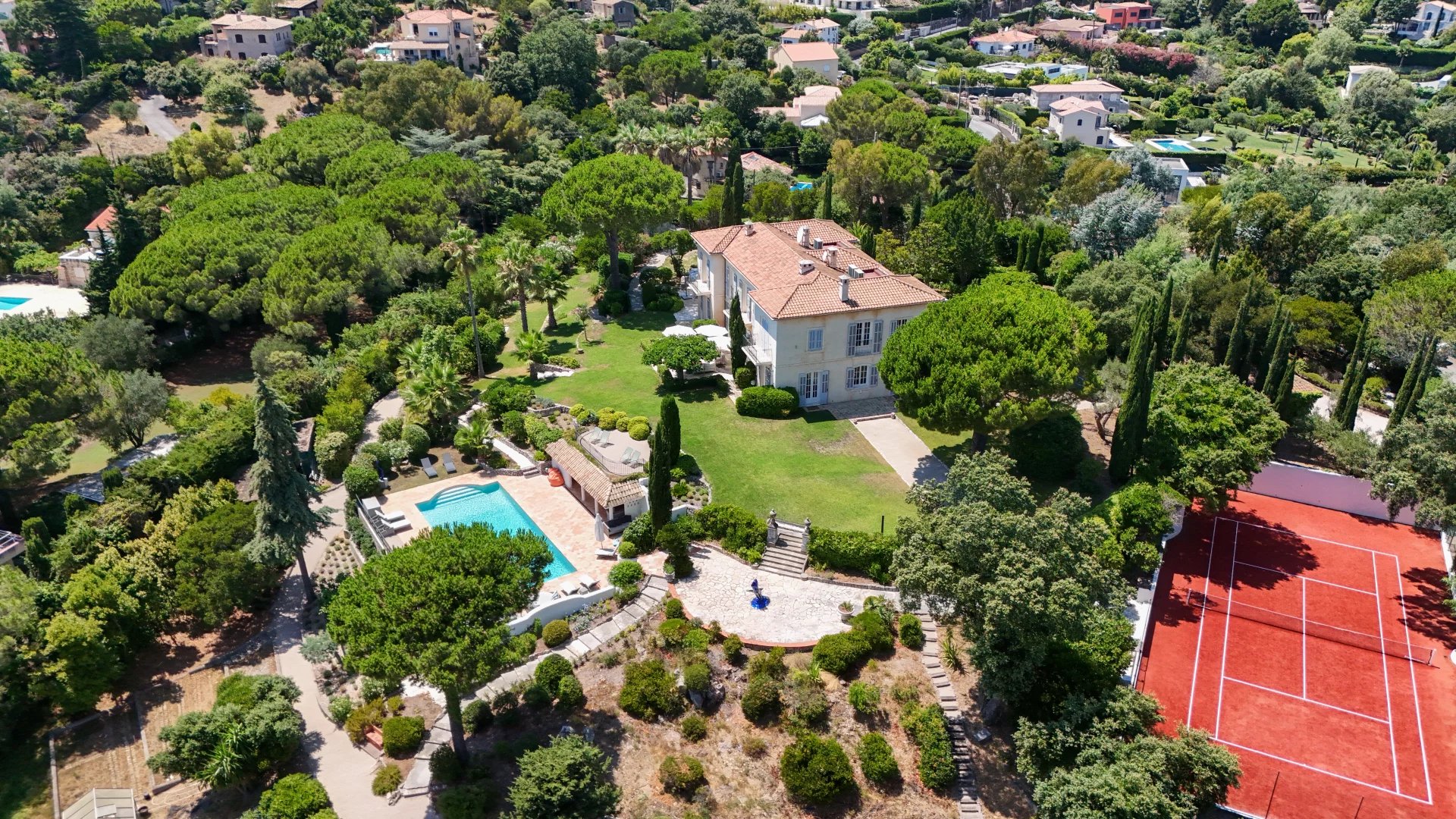 Aerial view of a villa with a pool and tennis court